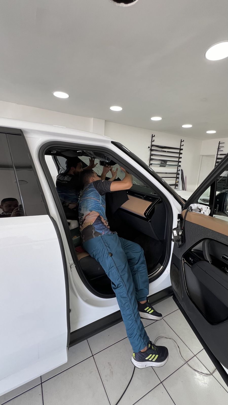 Dois técnicos da Center Films aplicando película no para-brisa de um Range Rover